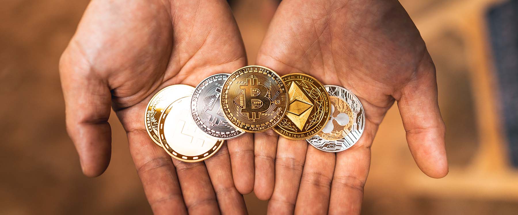 man's hands holding crytpocurrency coins